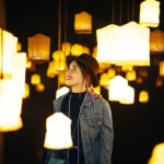 A closeup shot of a happy young lady in a room with many bright chandeliers