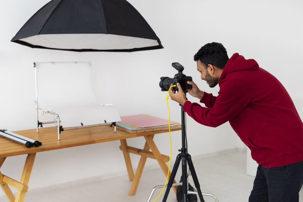 Photographer in a red hoodie clicking a picture in a studio